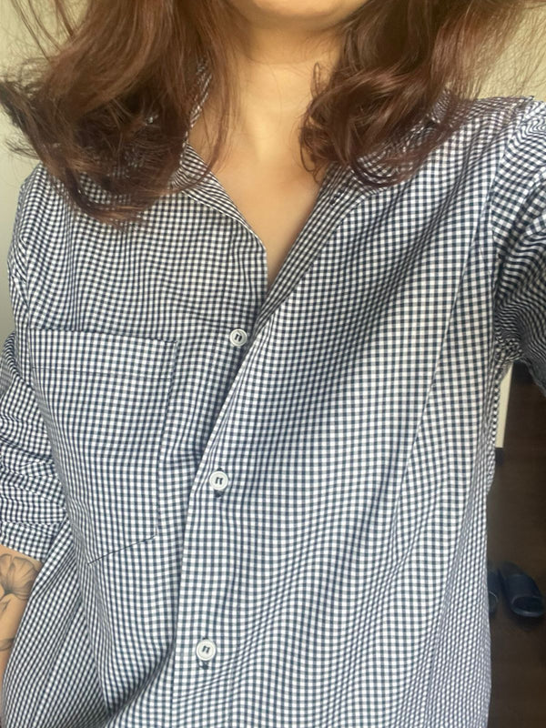 Person wearing a black and white checkered shirt with a blurred background