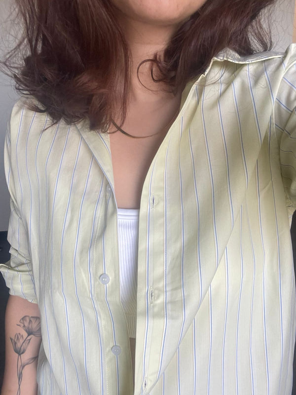 Person wearing a light green striped shirt with a plain background