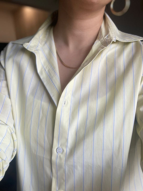Close-up of a person wearing a light-colored striped shirt with a blurred background